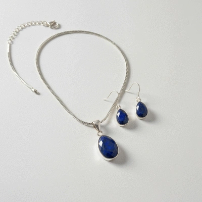 Collection of lapis lazuli jewelry, including a necklace and earrings, arranged on a neutral background
