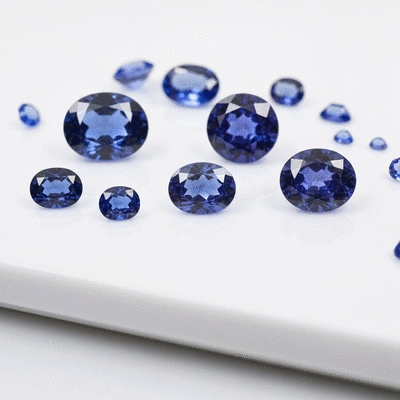 Assortment of various blue gemstones (tanzanite, iolite) arranged on a clean white surface, showcasing their unique colors and cuts, no text, no words, no typography, clean image