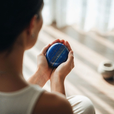 A serene meditation scene with a person holding a smooth lapis lazuli stone, surrounded by soft light, symbolizing inner peace and spiritual connection