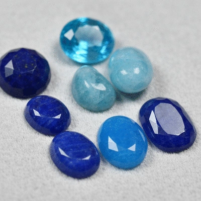 Close-up of various blue gemstones on a soft cloth, showcasing their vibrant hues and natural beauty.